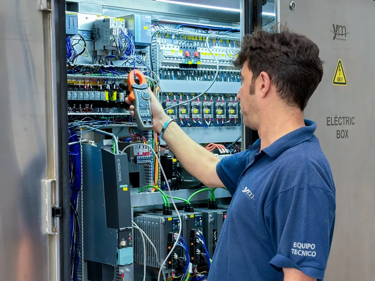 Técnico de YM Packaging midiendo con una pinza amperimétrica en el cuadro eléctrico de una máquina