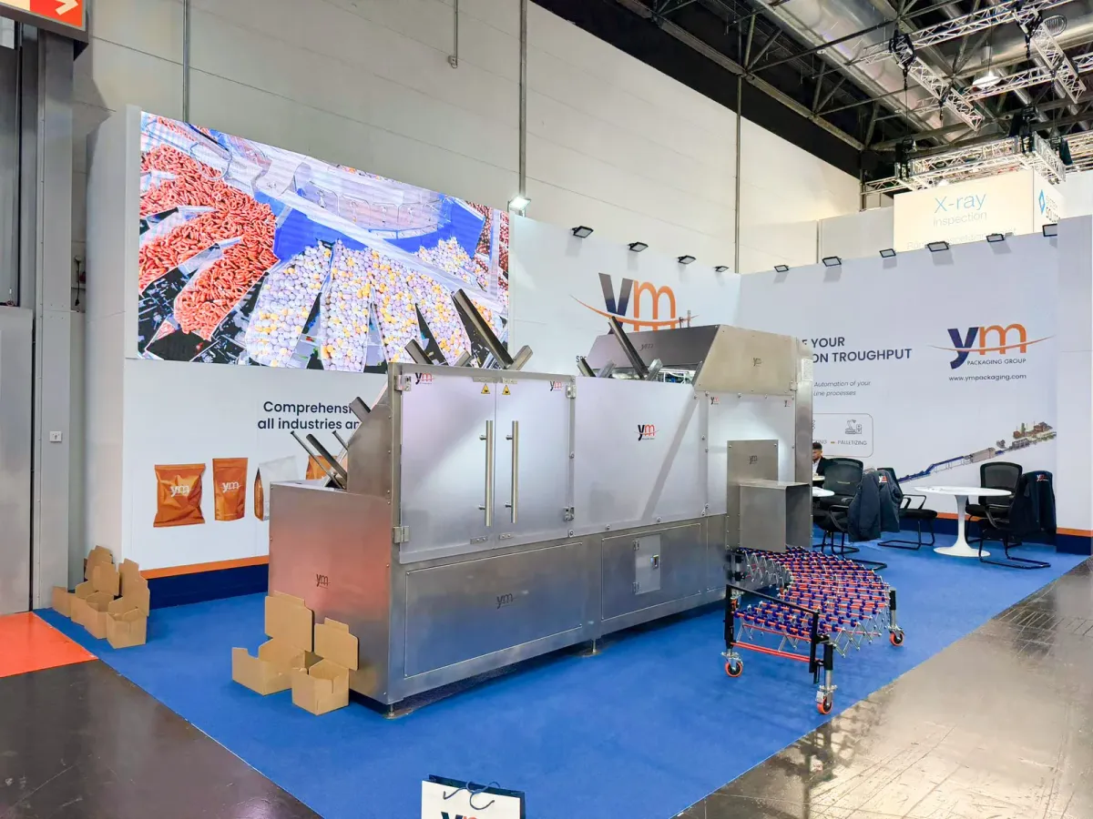 Stand de YM Packaging en interpack 2026 con la encajadora automática multiformato