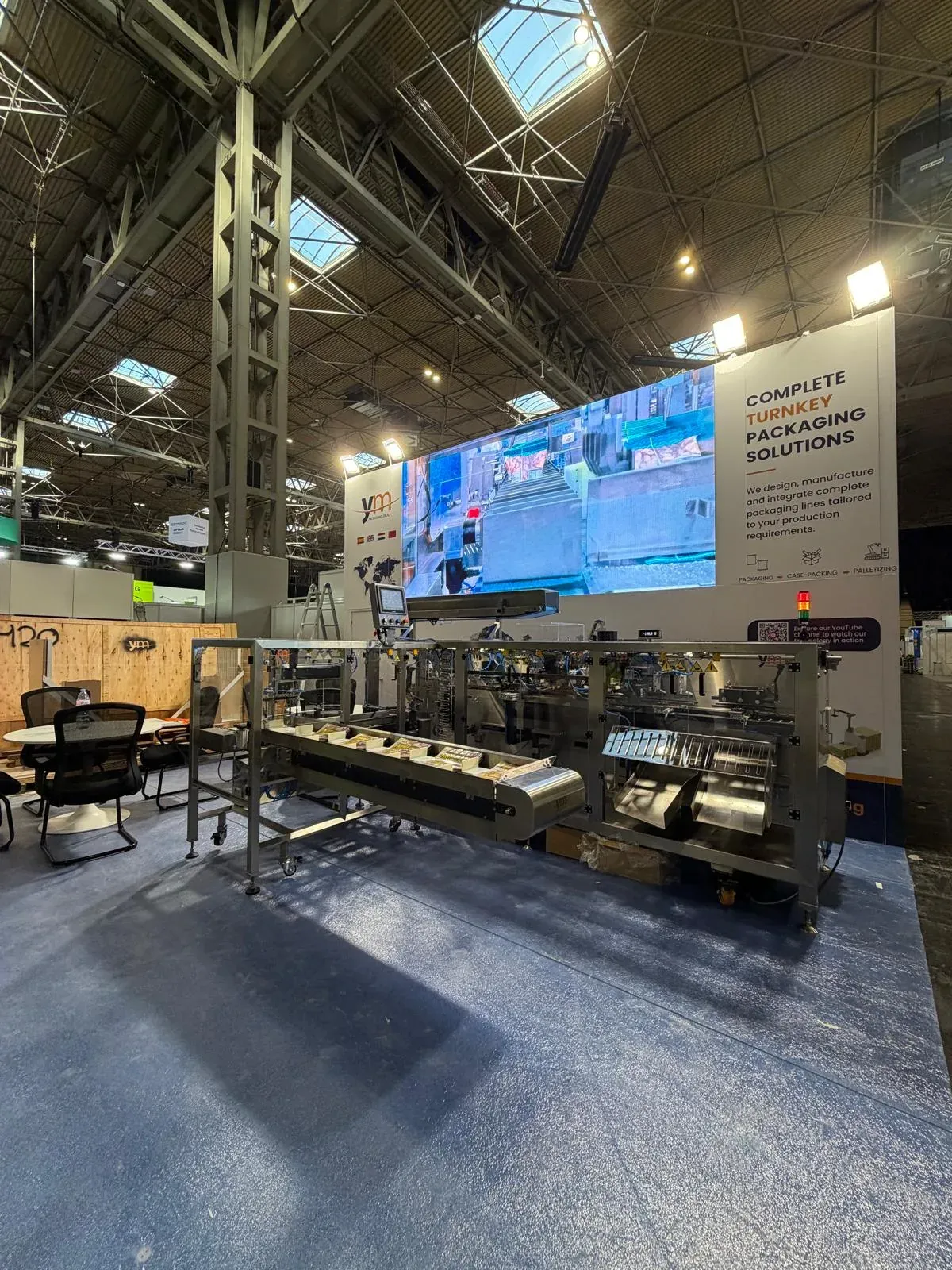 Stand de YM Packaging en PPMA 2026 con la envasadora y la pantalla LED