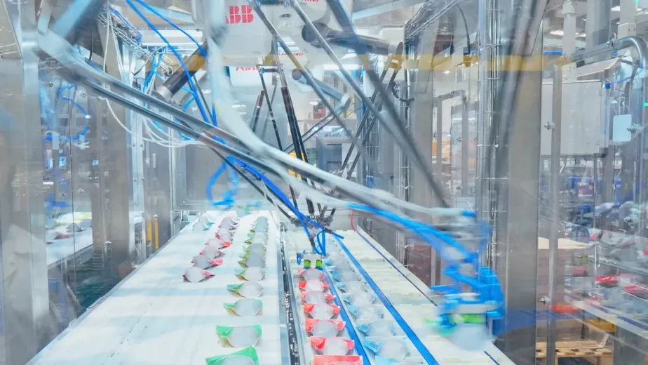 Robots delta ABB recogiendo bolsas de snacks de las cintas de entrada en una cabina de pick and place