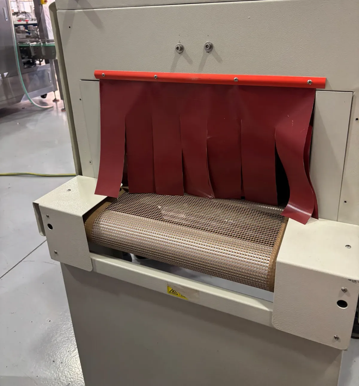 Infeed of the TR shrink tunnel with the silicone curtains and the perforated canvas belt